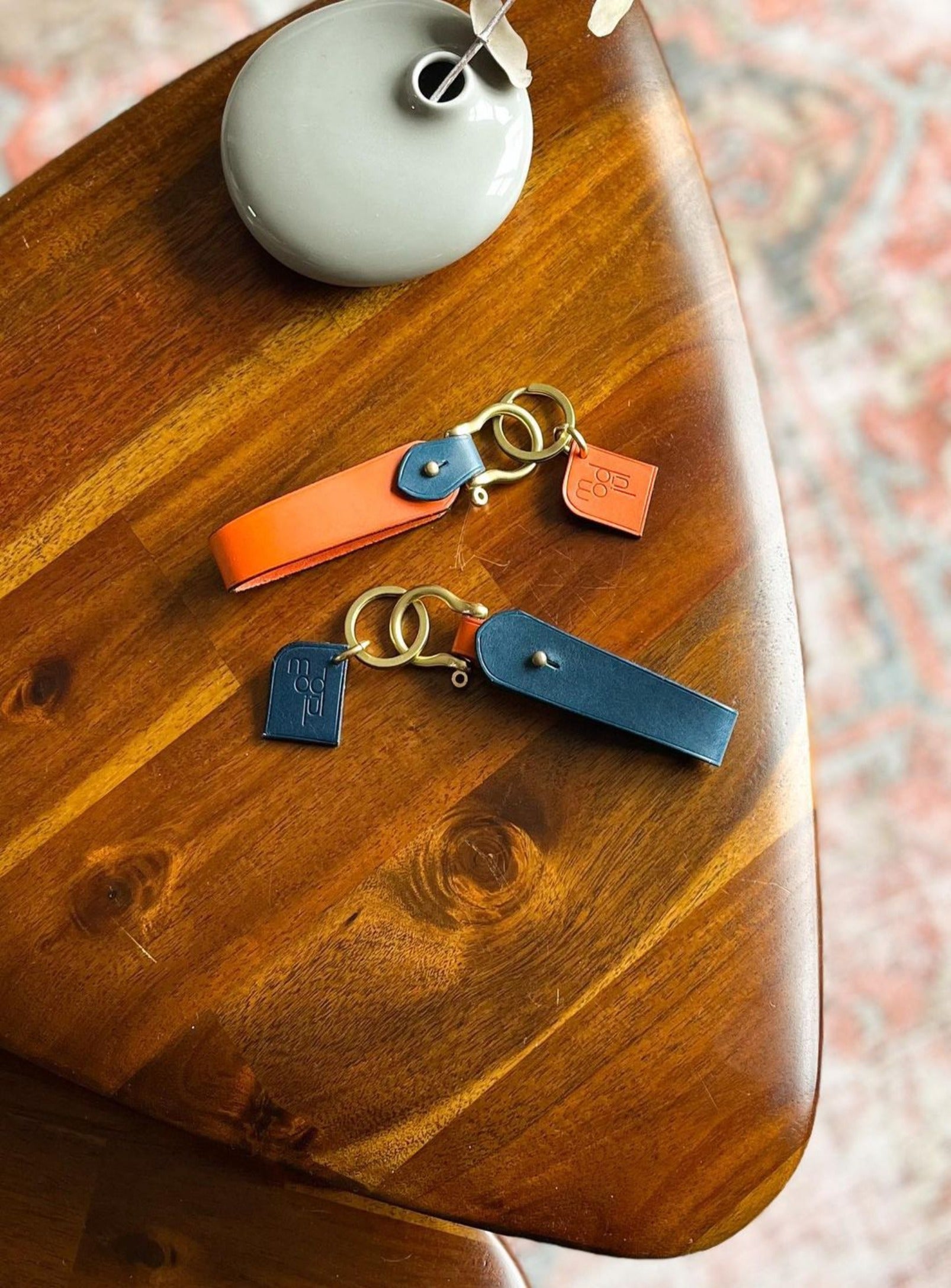 Two modjūl bi-color key links on top of a wooden table. 