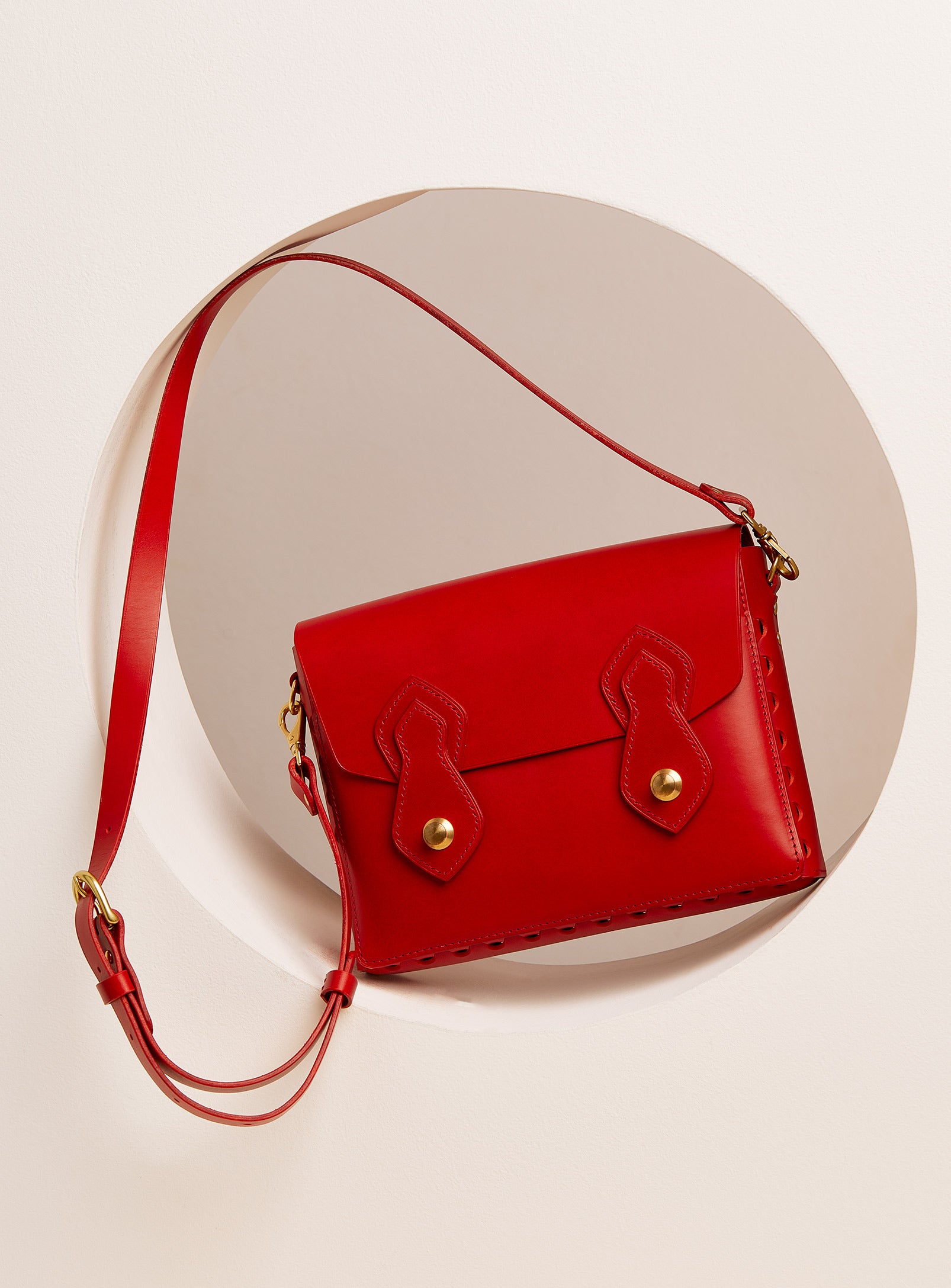 The modjūl odyssey bag in red. A large side bag with crossbody straps and double brass closure. Handcrafted in Canada using vegetable dyed Italian leather and quality brass hardware.