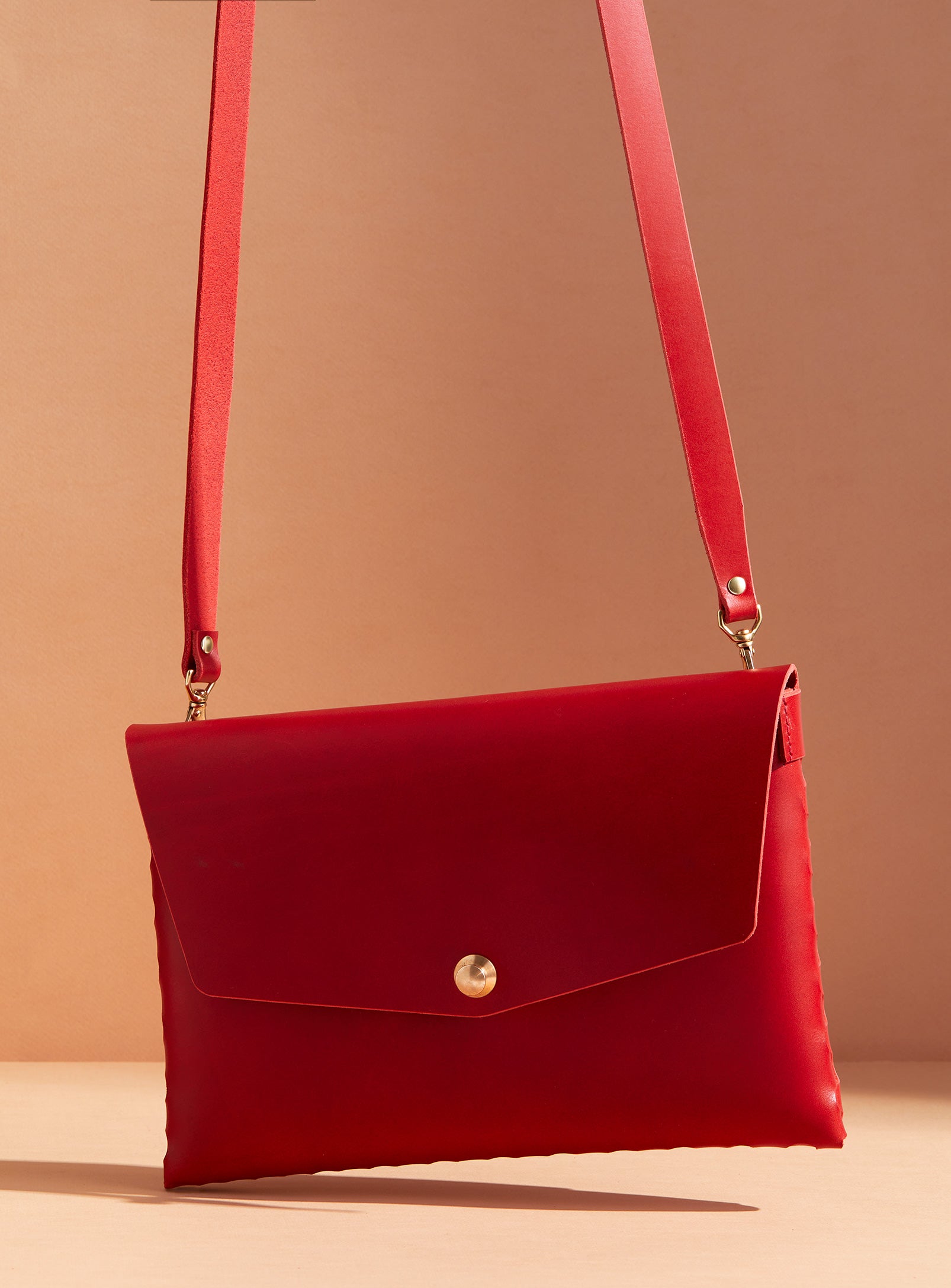 modjūl’s leather mini bag deluxe bag in red. A larger take on the classic mini bag, a rectangular-shaped bag with long detachable straps, handcrafted in Canada using quality Italian leather and brass hardware.