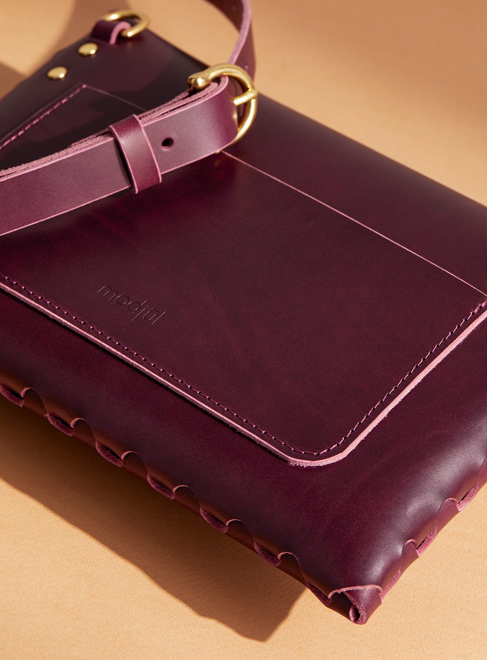 A close up of the back pocket detail on the mini bag deluxe handcrafted in Canada using burgundy Italian leather and quality brass hardware.