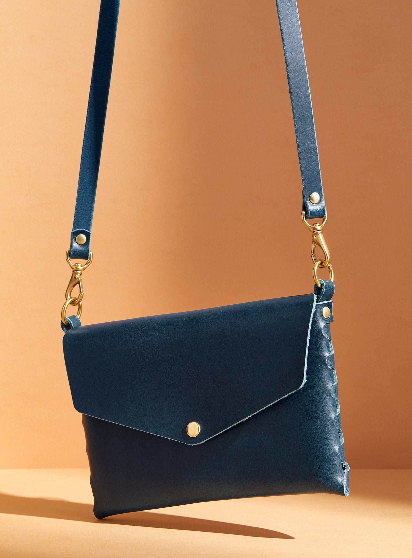 modjūl's mini leather bag in blue. A rectangular-shaped bag with long straps, handmade in Canada using quality Italian leather and brass hardware.