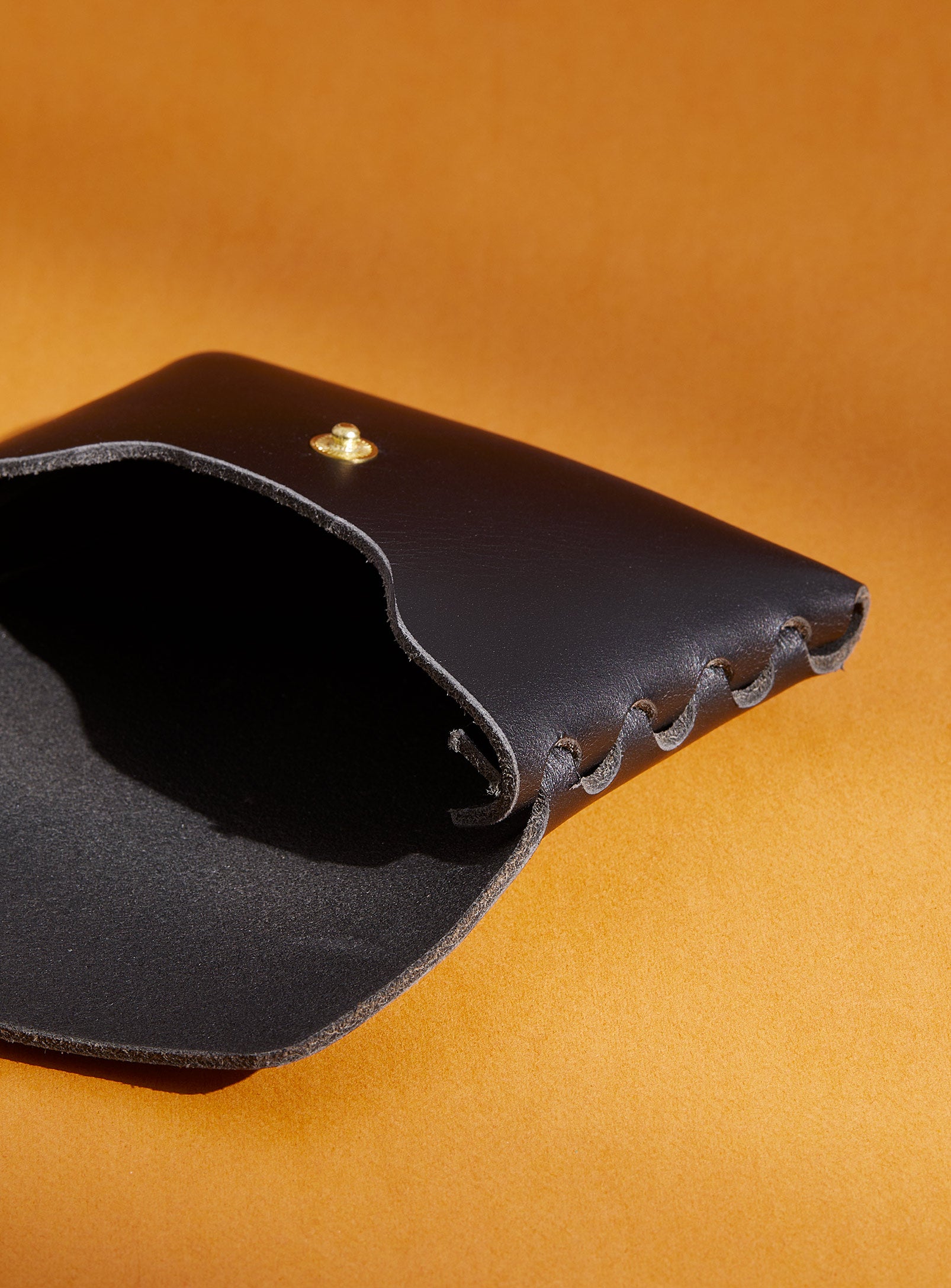 An inside look at modjūl's classic pouch in black leather. A compact open wallet with endless possibilities, perfect for holding cards, keys or loose change. Handmade in Canada and joined with the signature modjūl joinery and quality brass hardware.