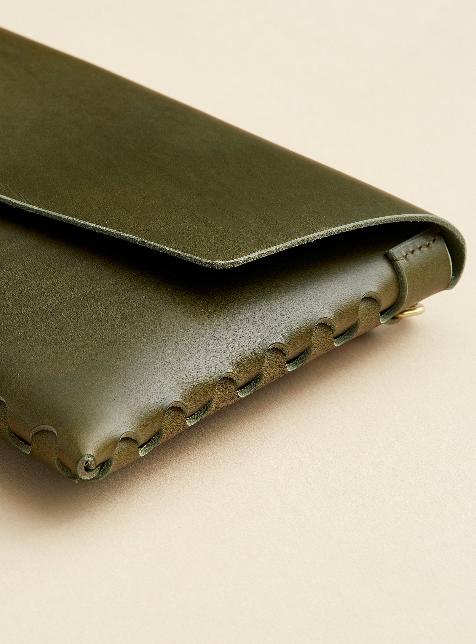 A close up of modjūl's signature joinery on the mini bag deluxe handcrafted in Canada using olive Italian leather and quality brass hardware.