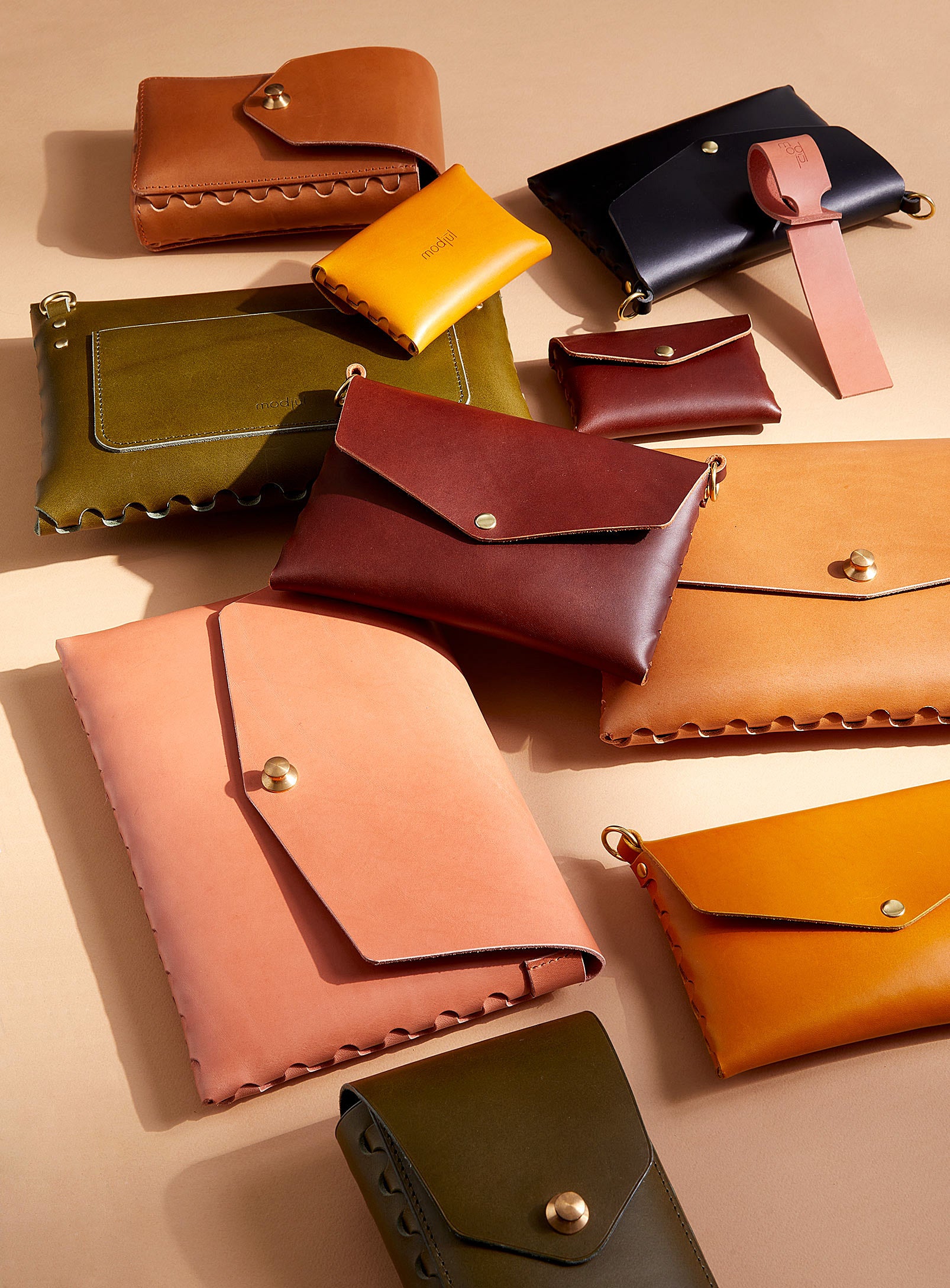 A collection of modjūl leather handbags, purses, crossbody bag and clutches scattered in a pile. 