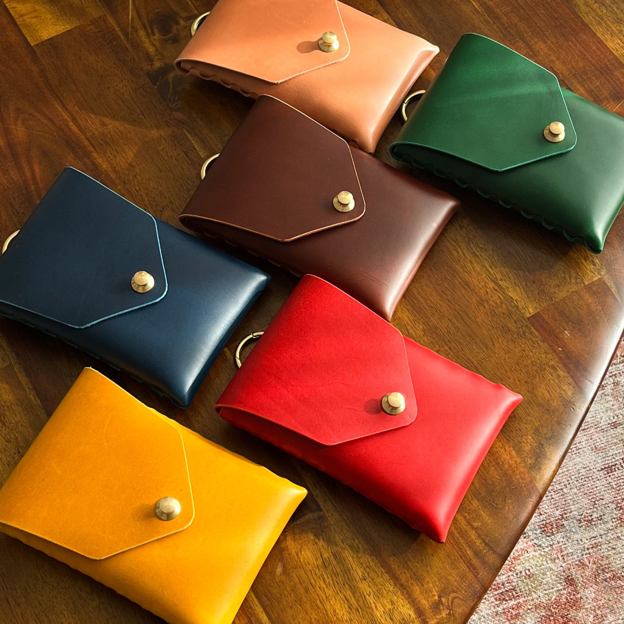 Mini leather capsule bags, hand crafted by modjūl studio in Canada all displayed in a rainbow of colors on a table.