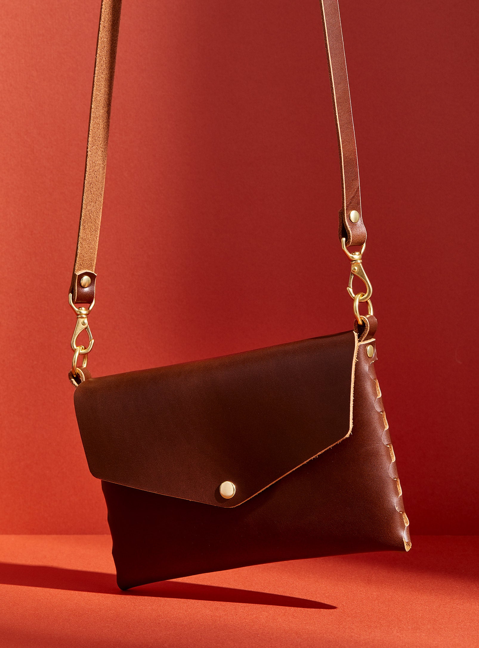 modjūl's mini leather bag in brown. A rectangular-shaped bag with long straps, handmade in Canada using quality Italian leather and brass hardware.