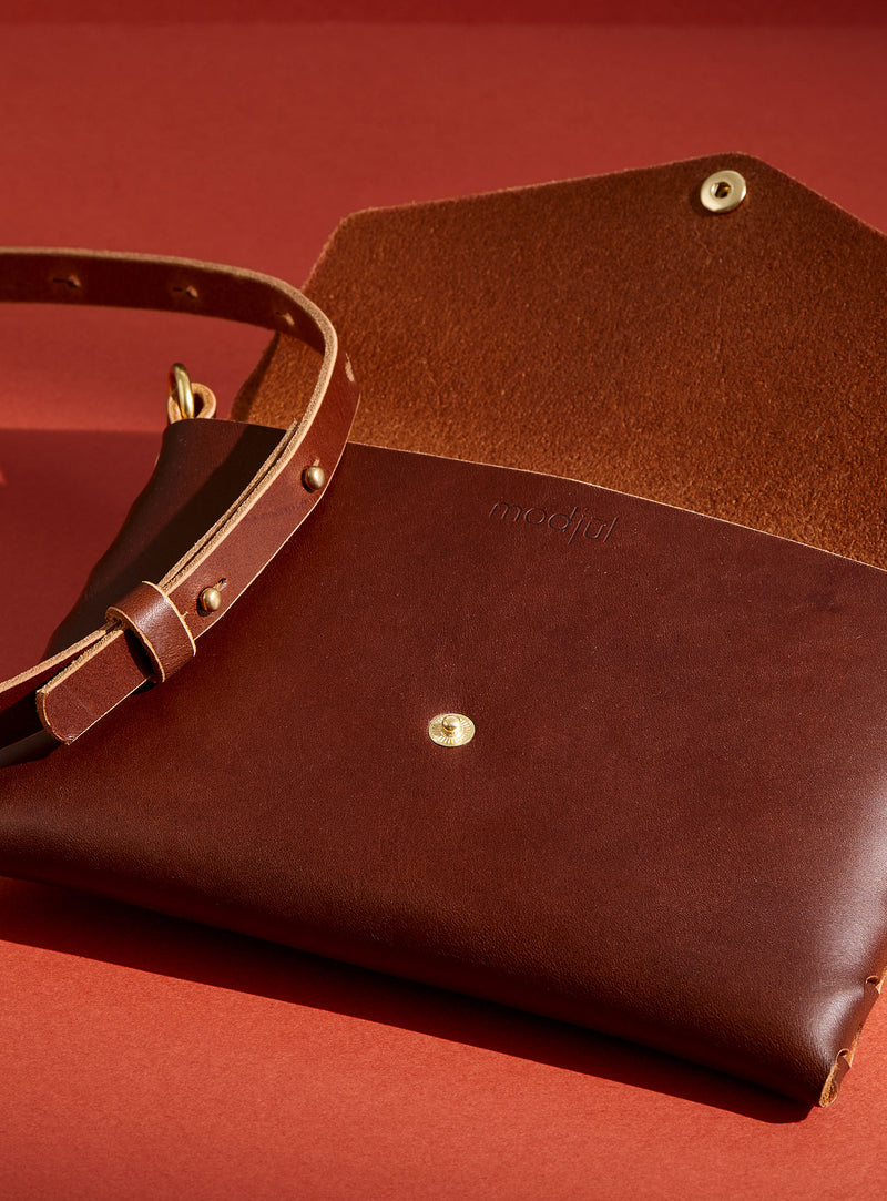 An inside look at modjūl's mini leather bag in brown. A rectangular-shaped bag with long straps, handmade in Canada using quality Italian leather and brass hardware.