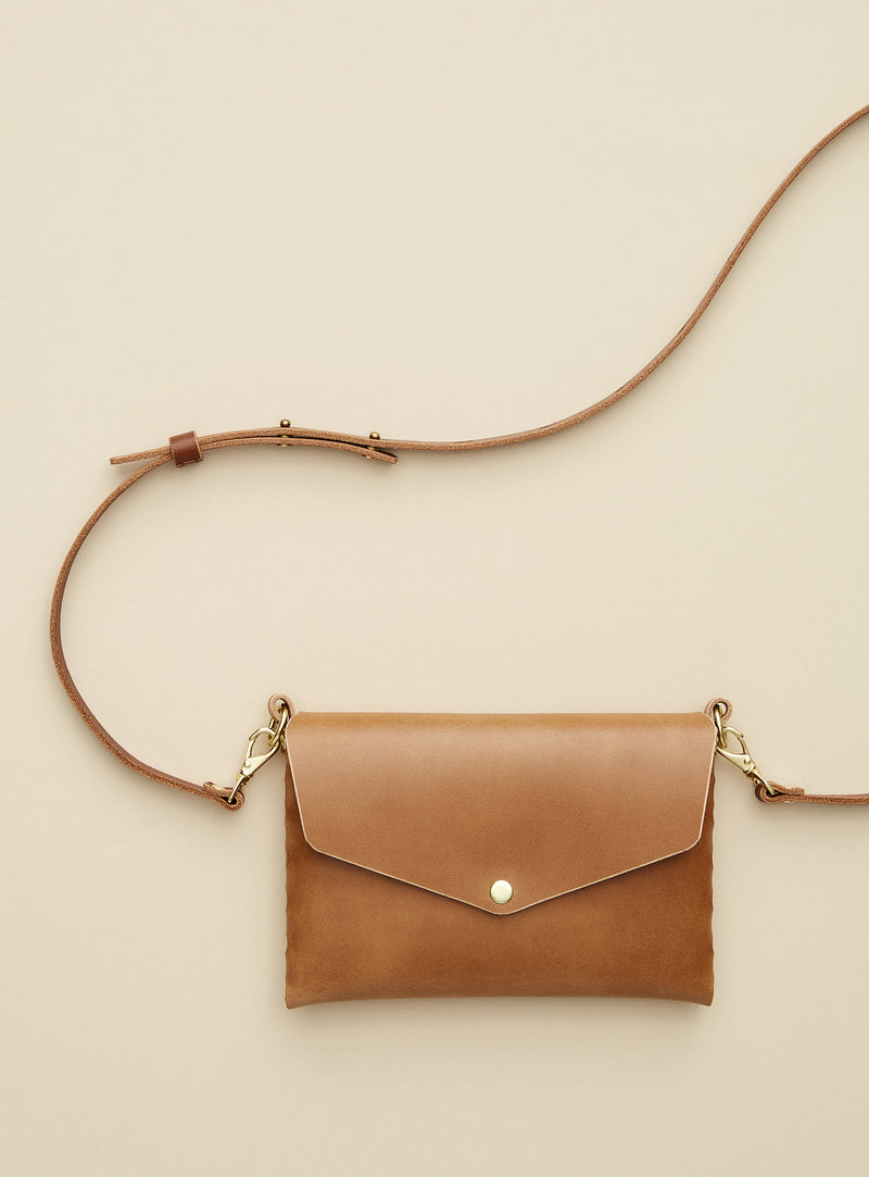modjūl's mini leather bag in camel. A rectangular-shaped bag with long straps, handmade in Canada using quality Italian leather and brass hardware.