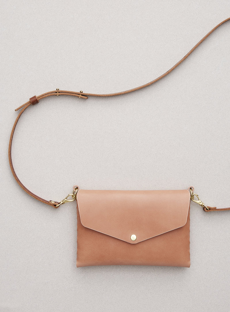 modjūl's mini leather bag in pink. A rectangular-shaped bag with long straps, handmade in Canada using quality Italian leather and brass hardware.