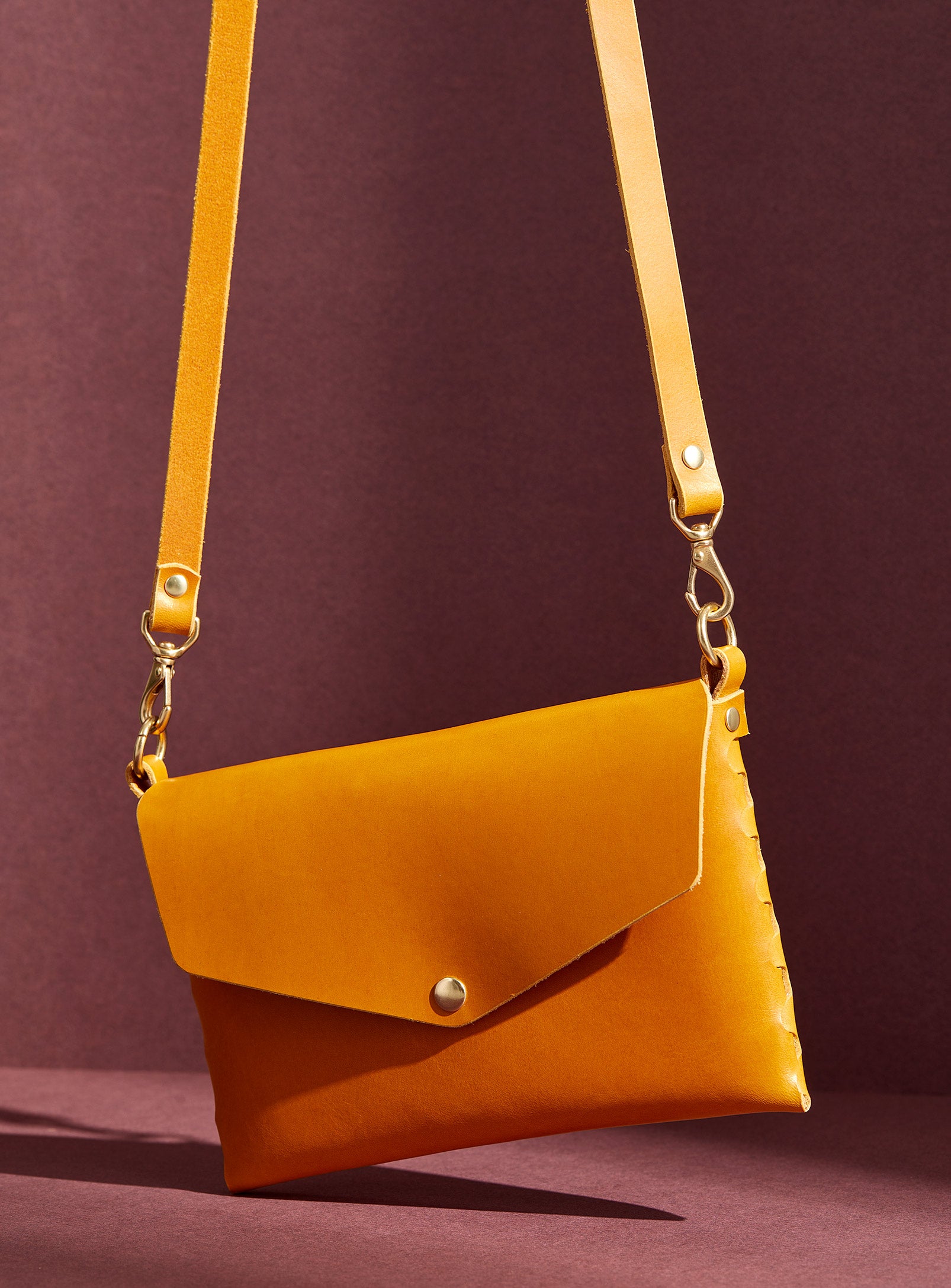 modjūl's mini leather bag in yellow. A rectangular-shaped bag with long straps, handmade in Canada using quality Italian leather and brass hardware.
