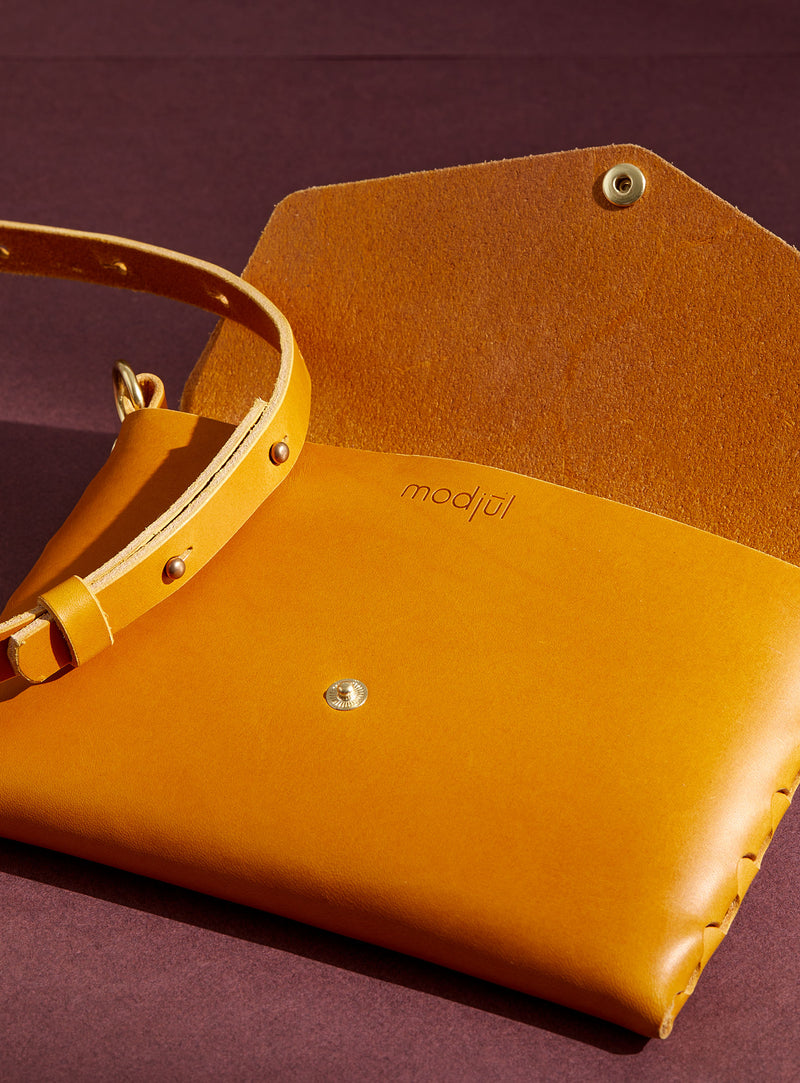 An inside view of modjūl's mini leather bag in yellow. A rectangular-shaped bag with long straps, handmade in Canada using quality Italian leather and brass hardware.