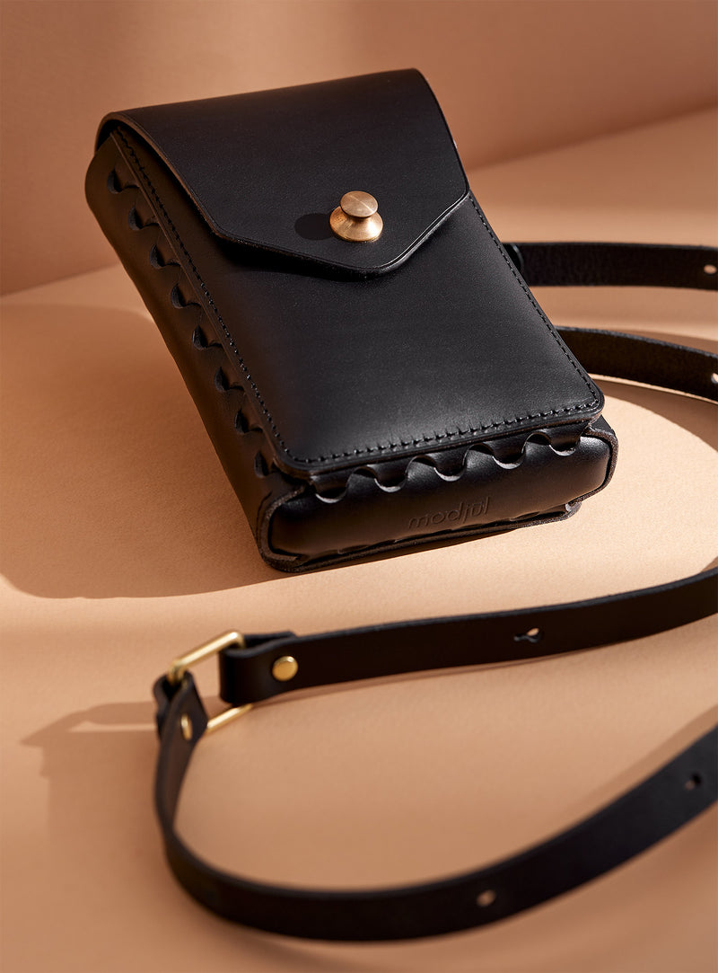 modjūl's capsule leather bag in black. A rectangular-shaped bag with long straps, perfect for a phone.