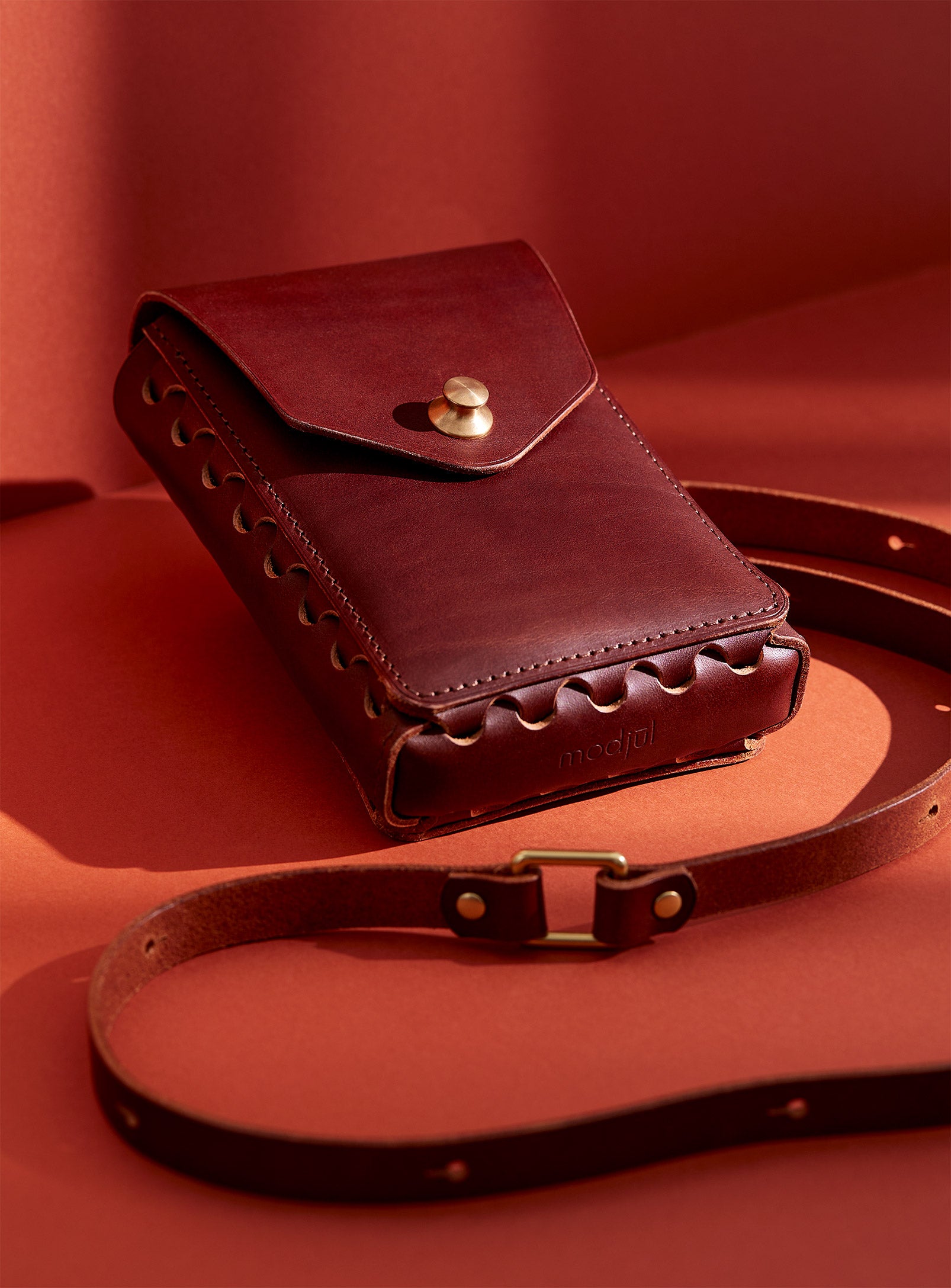 modjūl's capsule leather bag in brown. A rectangular-shaped bag with long straps, perfect for a phone.