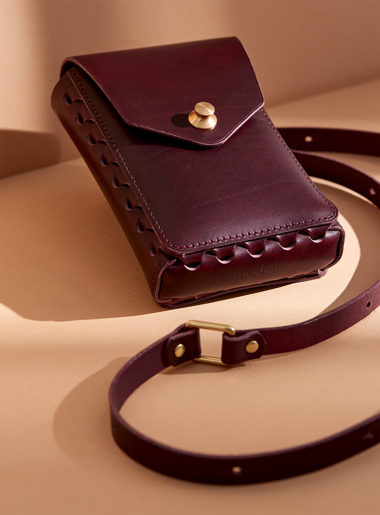 modjūl's capsule leather bag in burgundy. A rectangular-shaped bag with long straps, perfect for a phone.