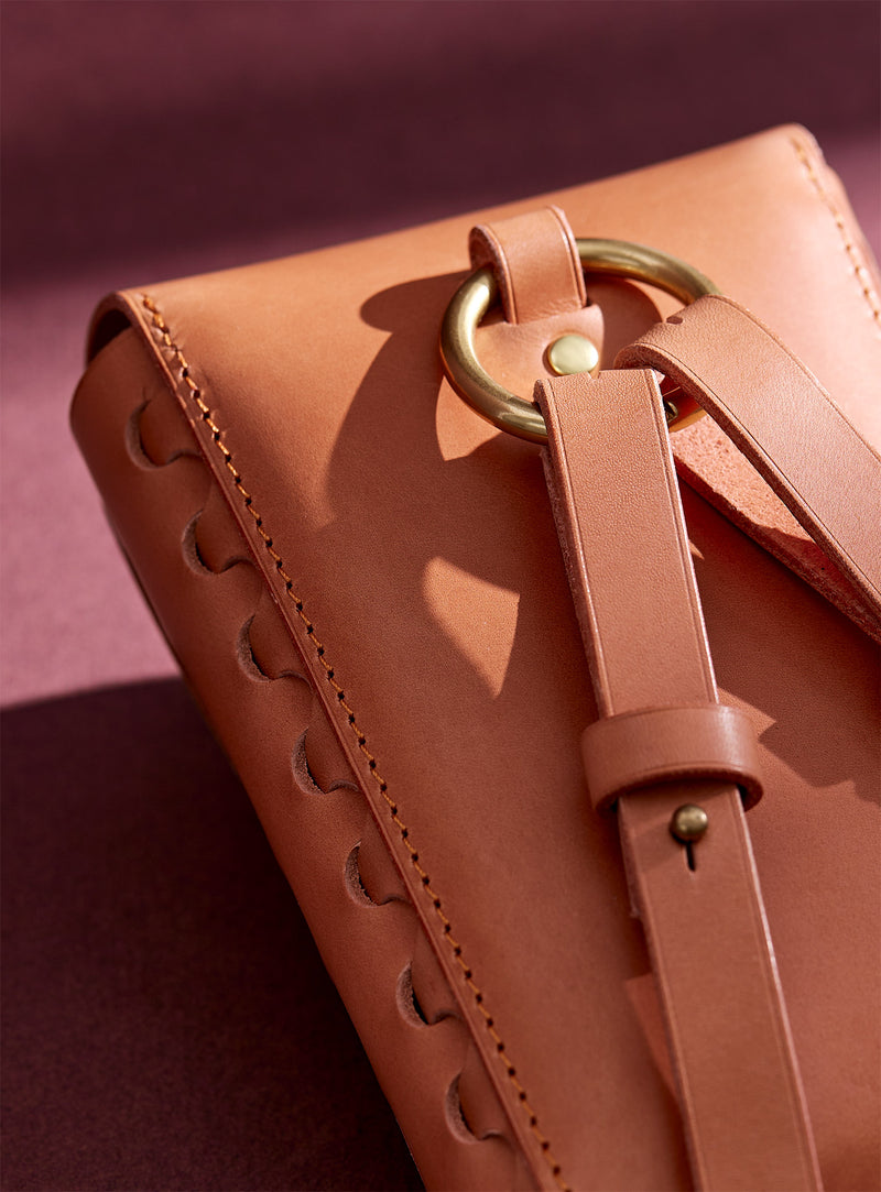 A close up of the back of modjūl's capsule leather bag showcasing metal hardware and leather straps.