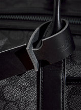 The modjūl leather traveller’s tag in black, displayed on a duffle bag. A luggage tag constructed using quality vegetable-dyed Italian leather with the option for personalization.