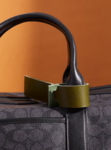 The modjūl leather traveller’s tag in olive, displayed on a duffle bag. A luggage tag constructed using quality vegetable-dyed Italian leather with the option for personalization.