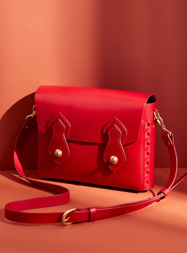 The modjūl odyssey bag in red. A large side bag with crossbody straps and double brass closure. Handcrafted in Canada using vegetable dyed Italian leather and quality brass hardware. 