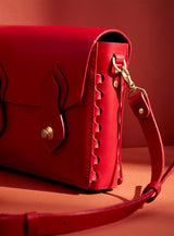 The side profile of the Odyssey bag in red vegetable dyed Italian leather, showcasing modjūl's signature joinery and premium brass hardware. Experience the feeling of quality.