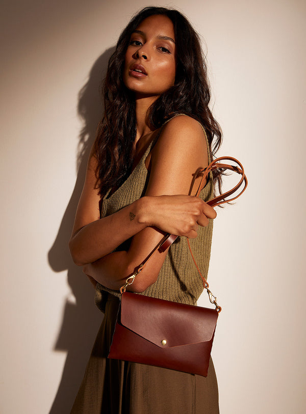 A woman holding the modjūl mini bag in brown leather.