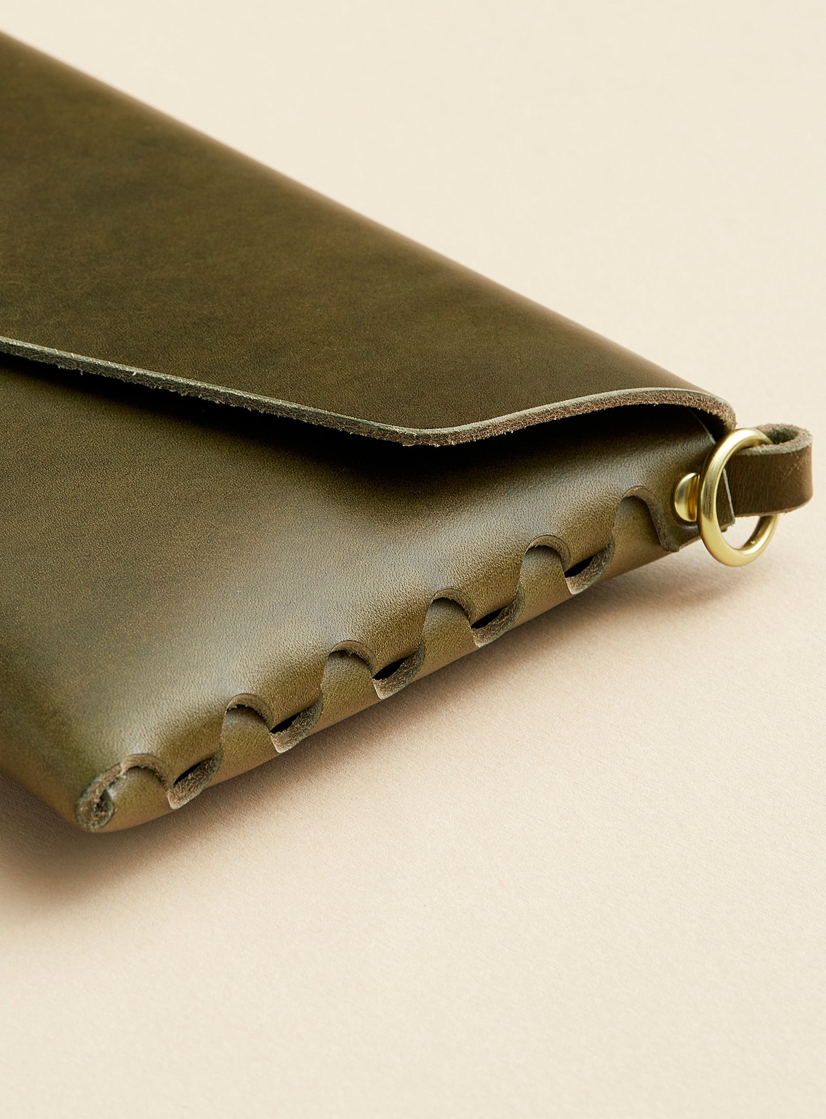 A close-up of modjūl's signature joinery on the leather mini bag in olive. Handmade in Canada using vegetable dyed leather and quality brass hardware.