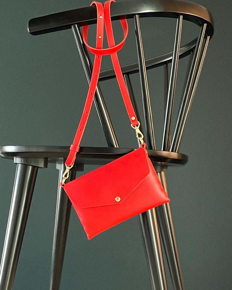 The modjūl mini bad in red hanging on the back of a chair. Handmade in Canada using premium Italian leather.