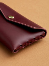 A side profile view of modjūl's classic pouch in burgundy leather. A compact open wallet with endless possibilities, perfect for holding cards, keys or loose change. Handmade in Canada and joined with the signature modjūl joinery and quality brass hardware.