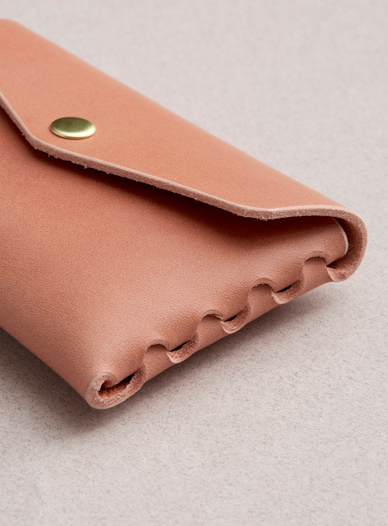 The side profile of modjūl's classic pouch in pink leather. A compact open wallet with endless possibilities, perfect for holding cards, keys or loose change. Handmade in Canada and joined with the signature modjūl joinery and quality brass hardware.
